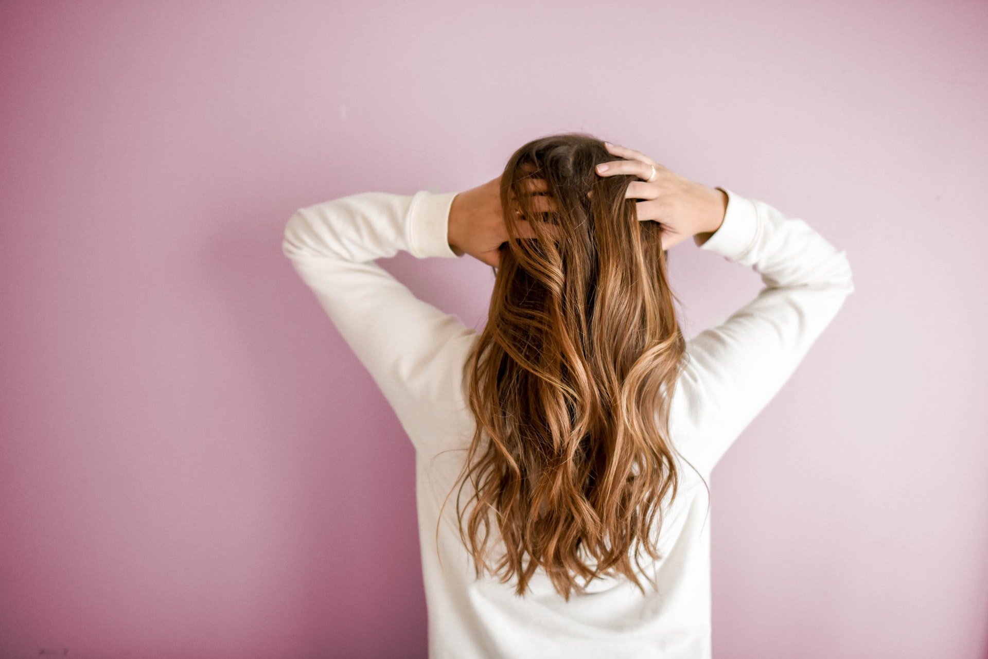 woman facing a wall with loose hair. healthy hair