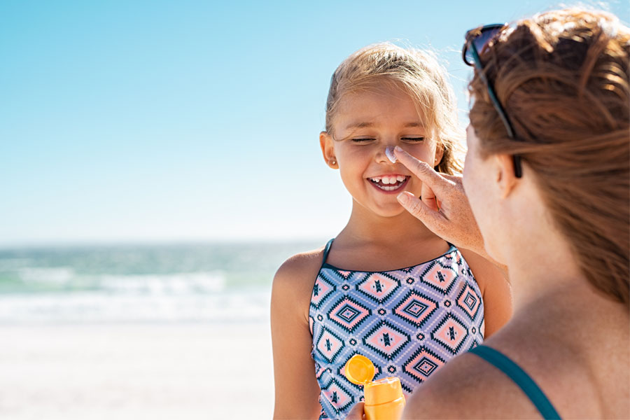 woman applying sunscreen to her daughter on beach. tips to getting rid of acne