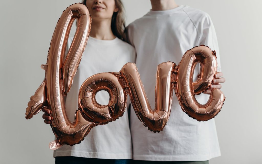couple holding balloon which spells love