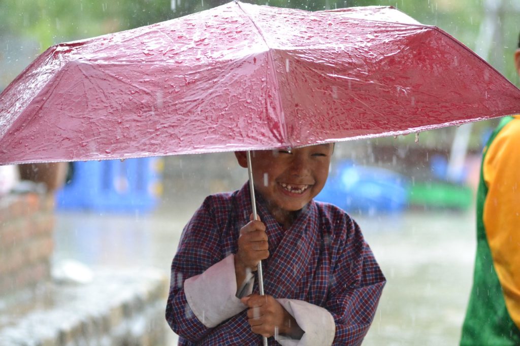 child laughing in rain under an umbrella