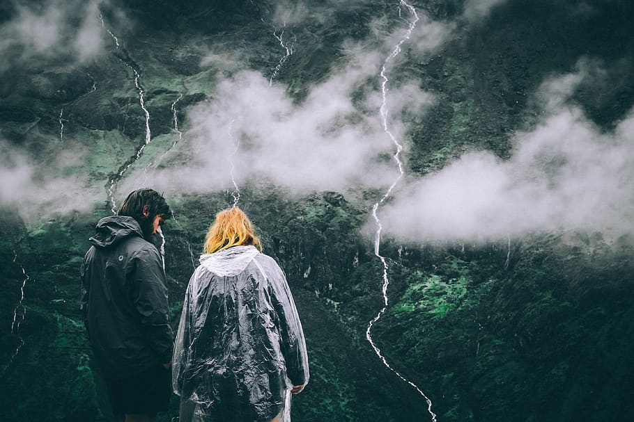 couple standing atop a mountain in monsoons