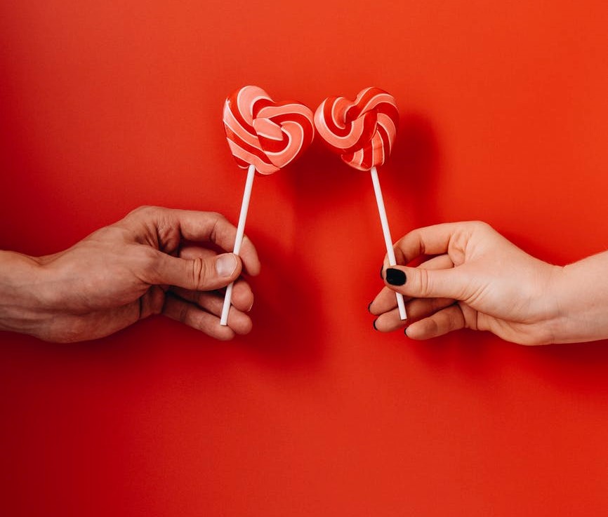 heart shaped lollies being  held by a couple